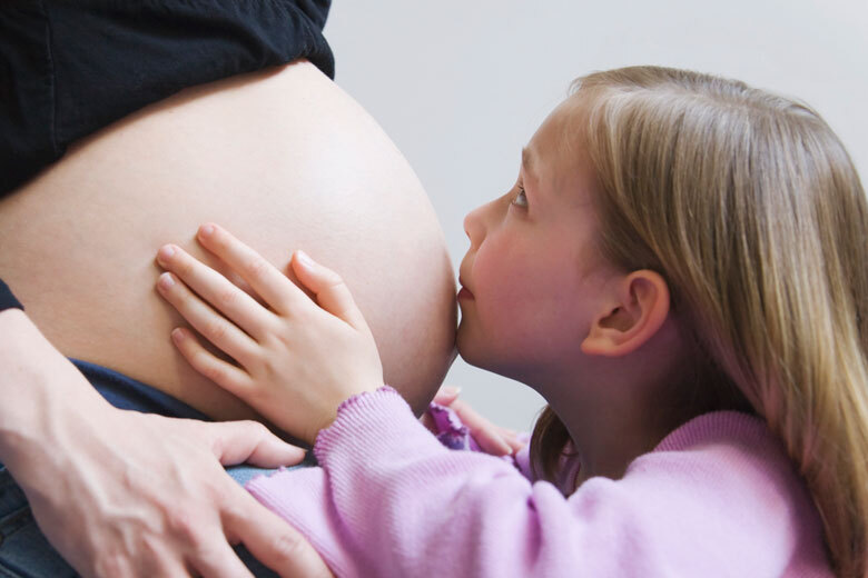 Kind küsst einen Schwangerschaftsbauch
